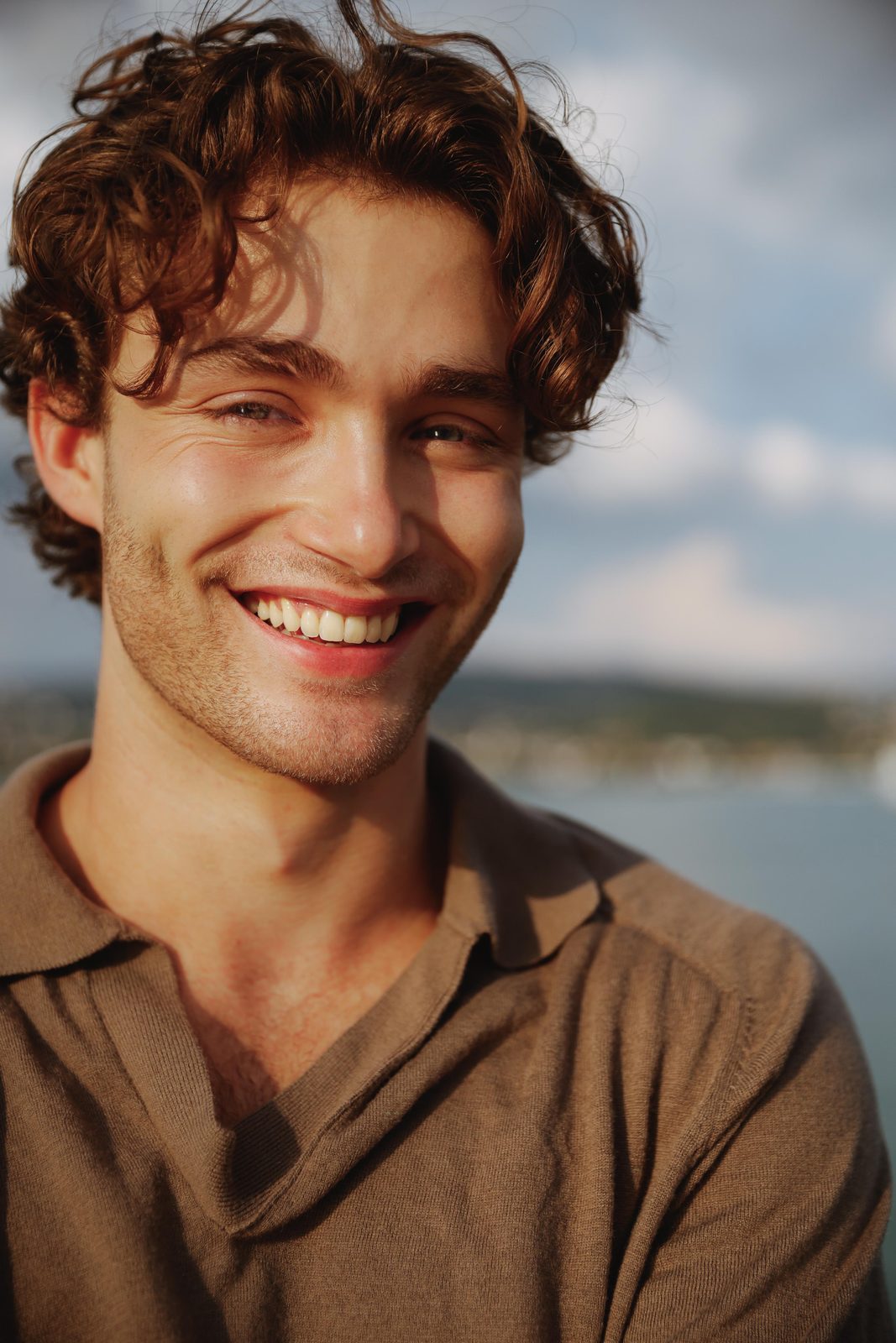 Pascal Sander smiling by the lake in a brown polo shirt
