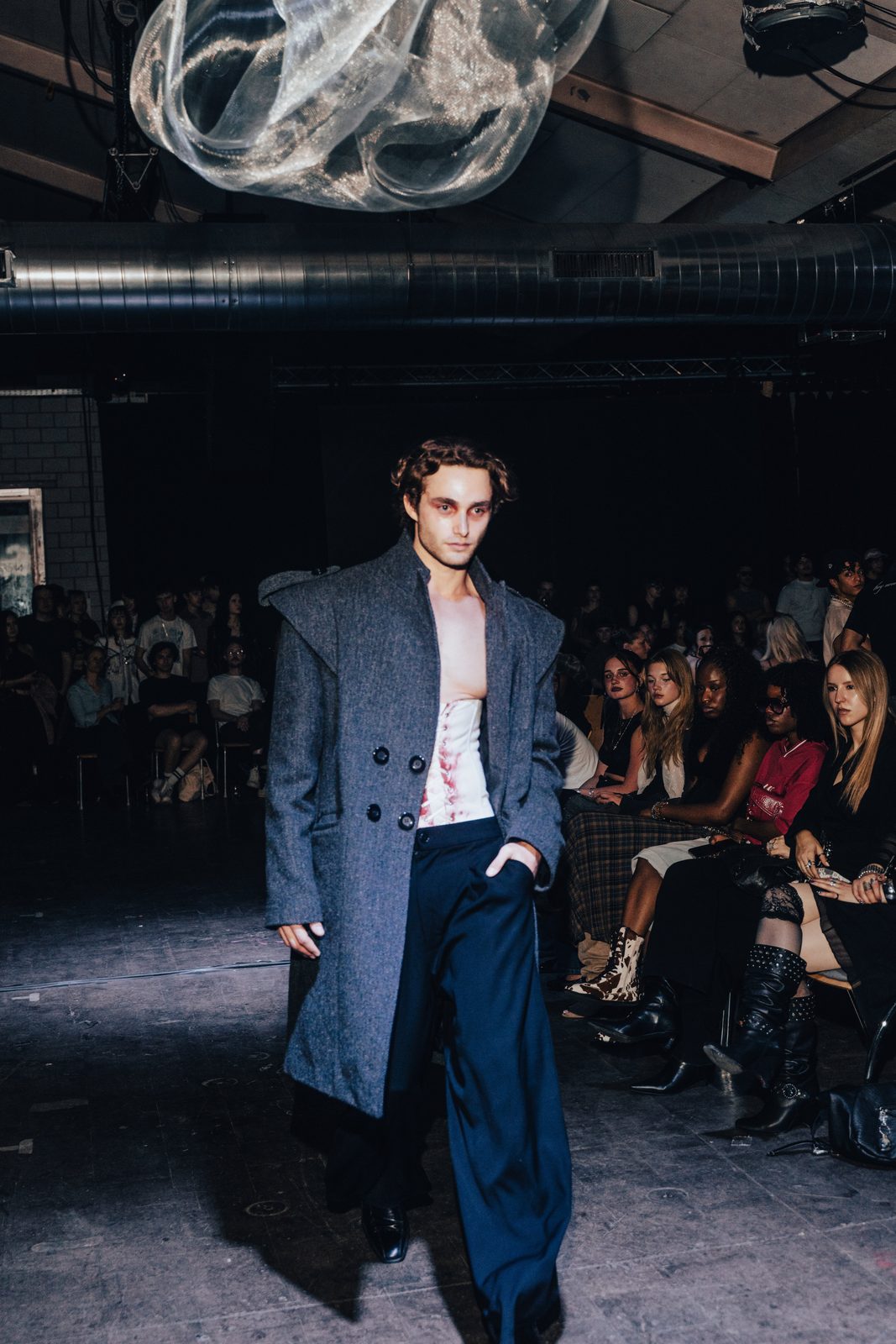 Pascal Sander walking a runway show in an oversized grey coat
