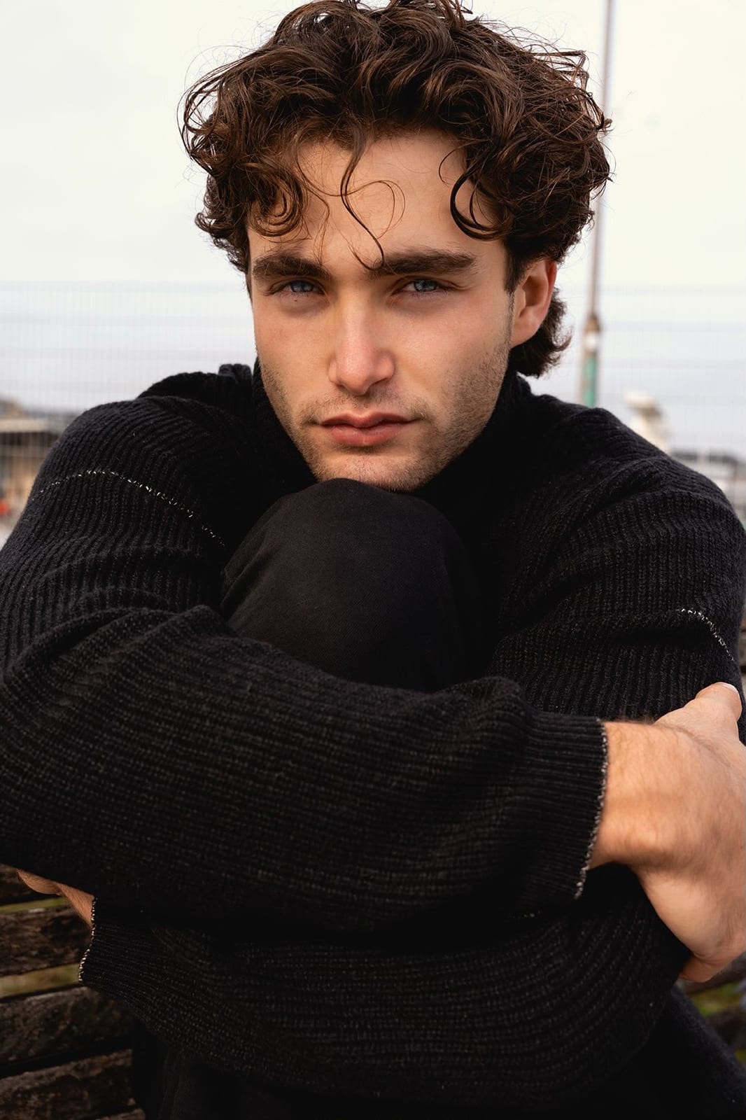 Pascal Sander in a black turtleneck, curly hair, harbour background