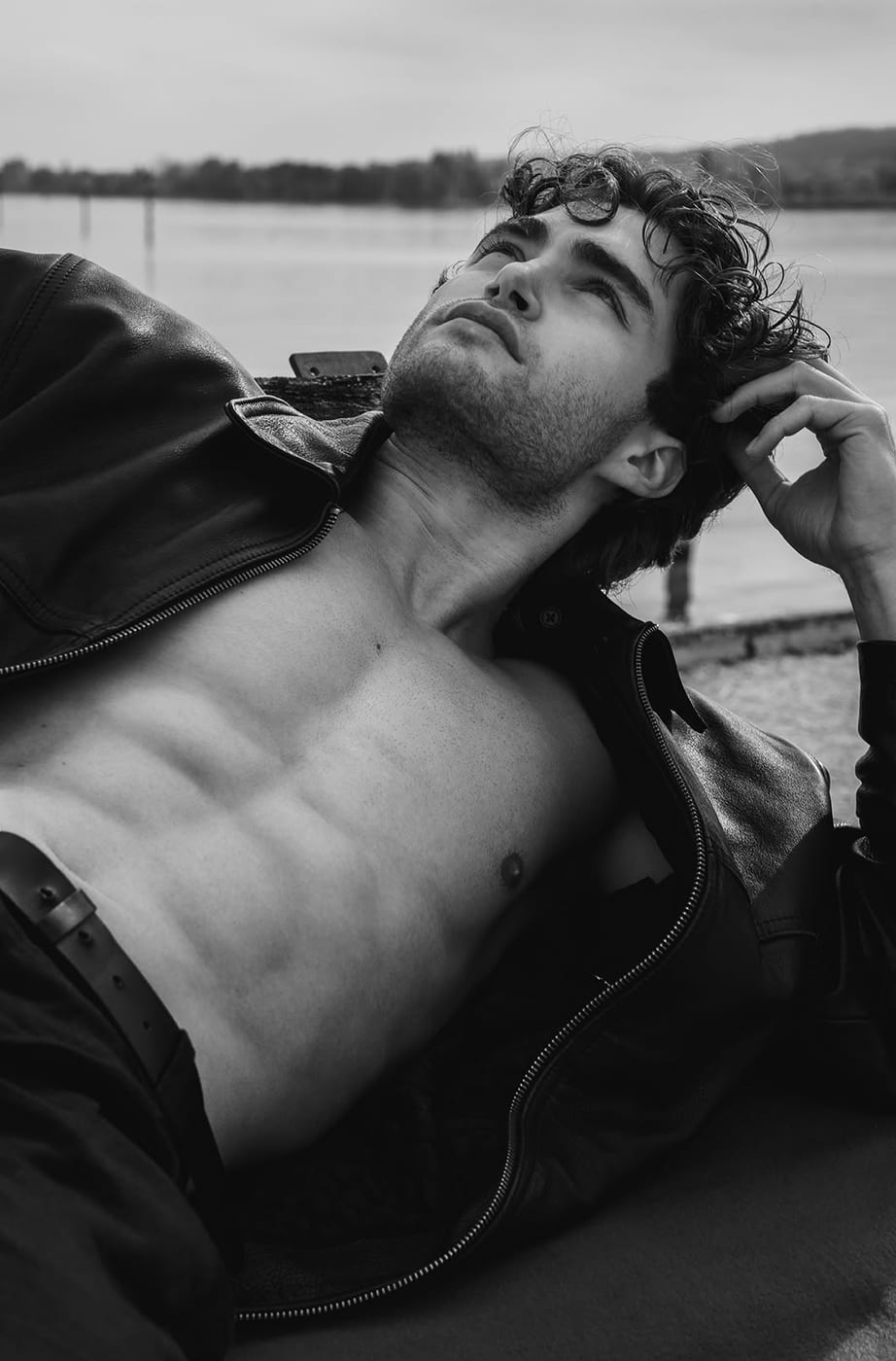 Pascal Sander shirtless by the water, chin resting on his hand