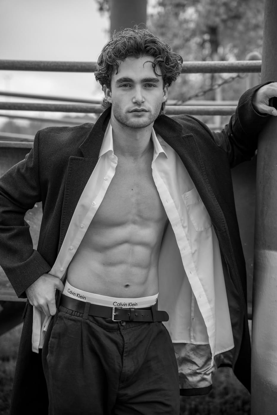 Pascal Sander in an open white shirt leaning by a window