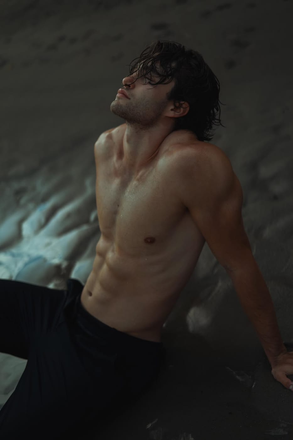 Pascal Sander shirtless, seated in a moody studio