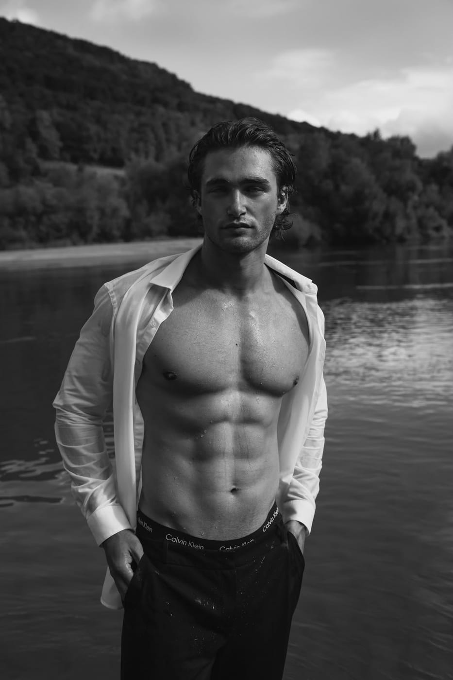 Pascal Sander in an open white shirt by a lake
