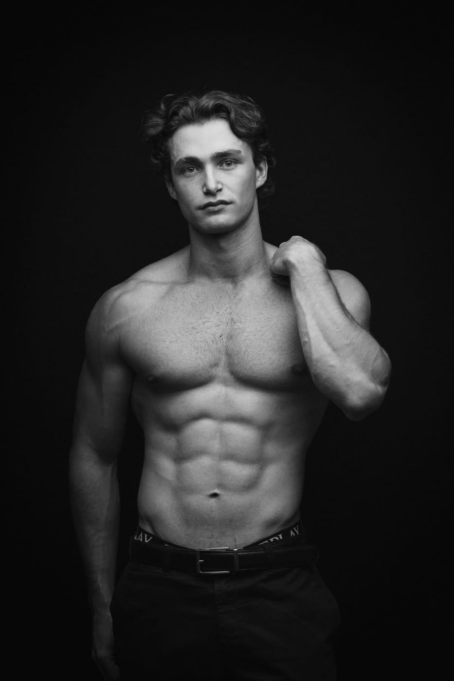 Pascal Sander shirtless with a jacket over one shoulder, dark studio