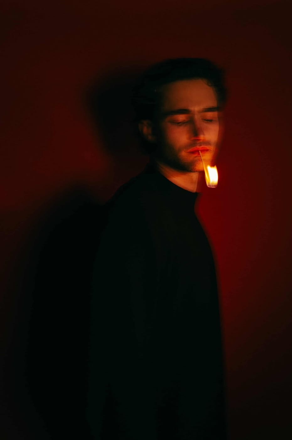 Pascal Sander in deep red light, holding a small flame