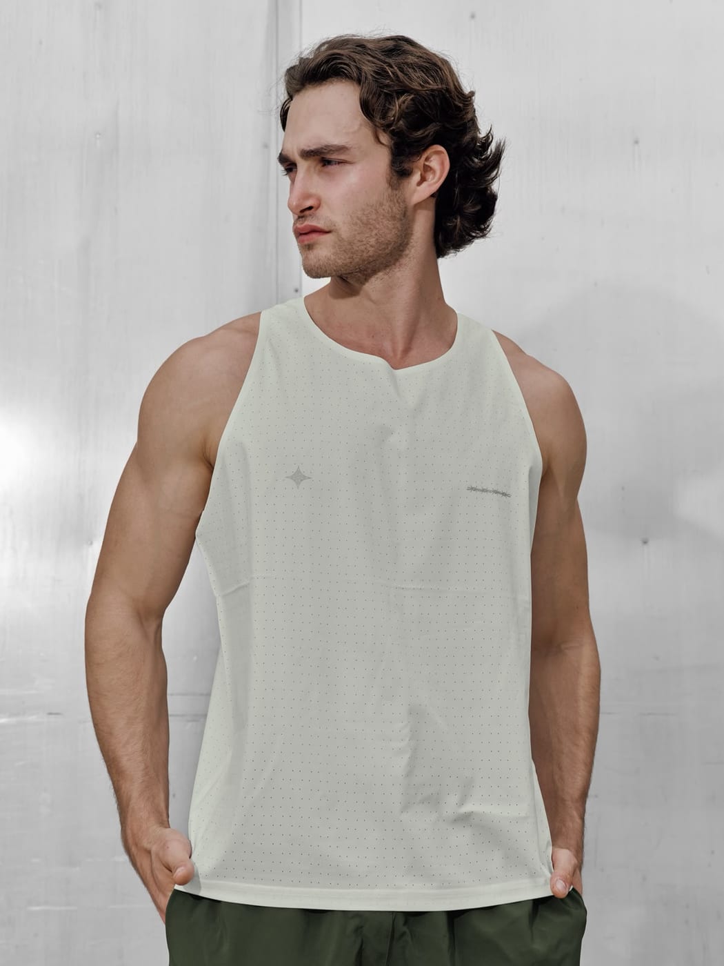 Pascal Sander in a white tank top against a textured wall