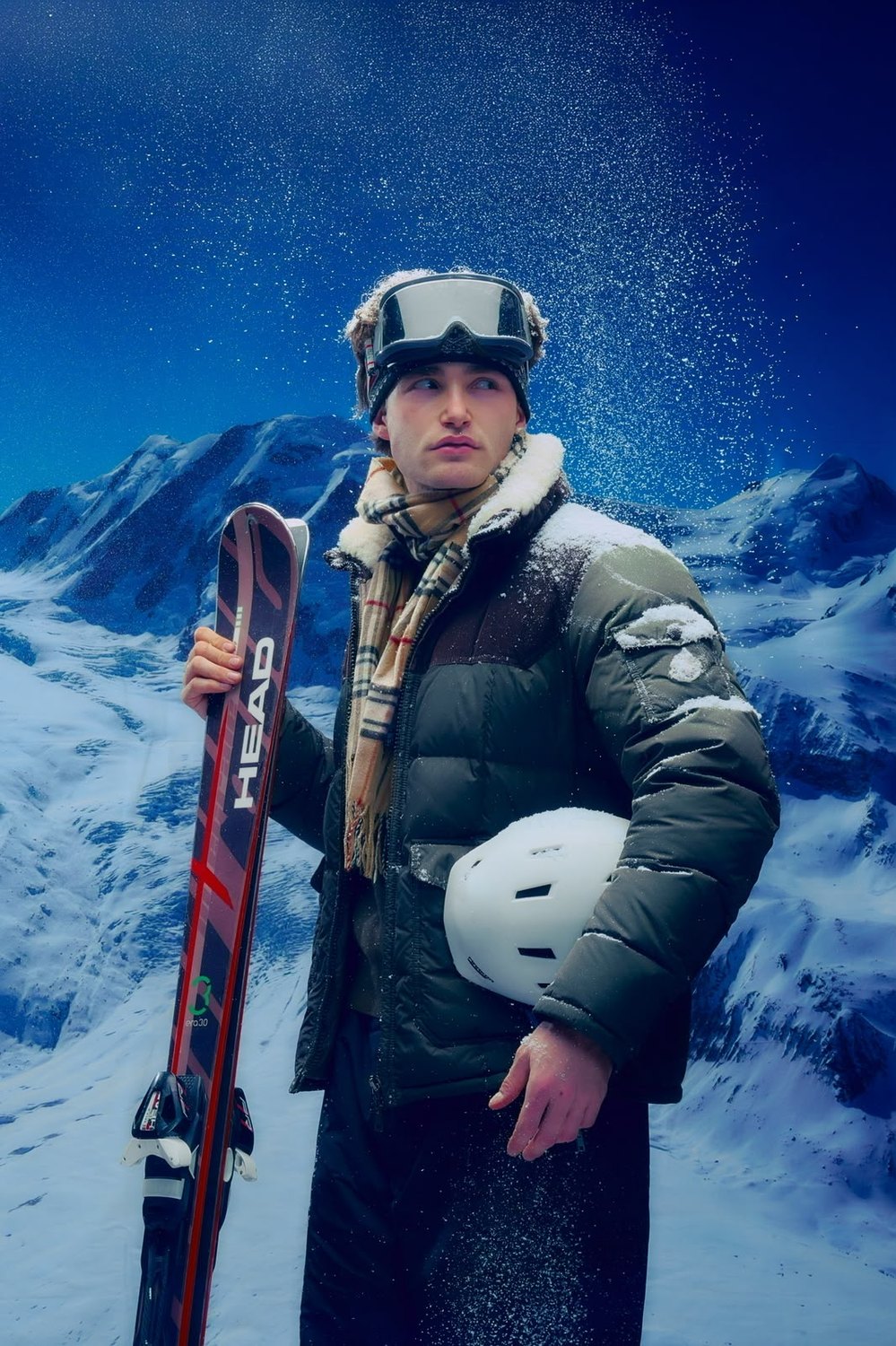 Pascal Sander in ski gear holding skis and a helmet in falling snow
