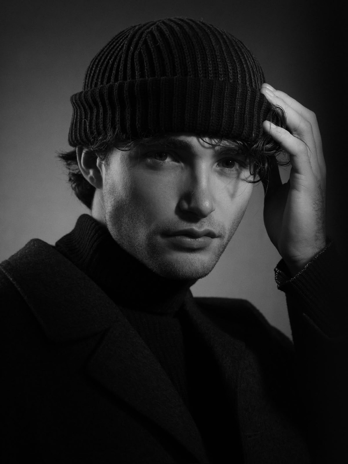Pascal Sander in a beanie and dark coat, studio portrait