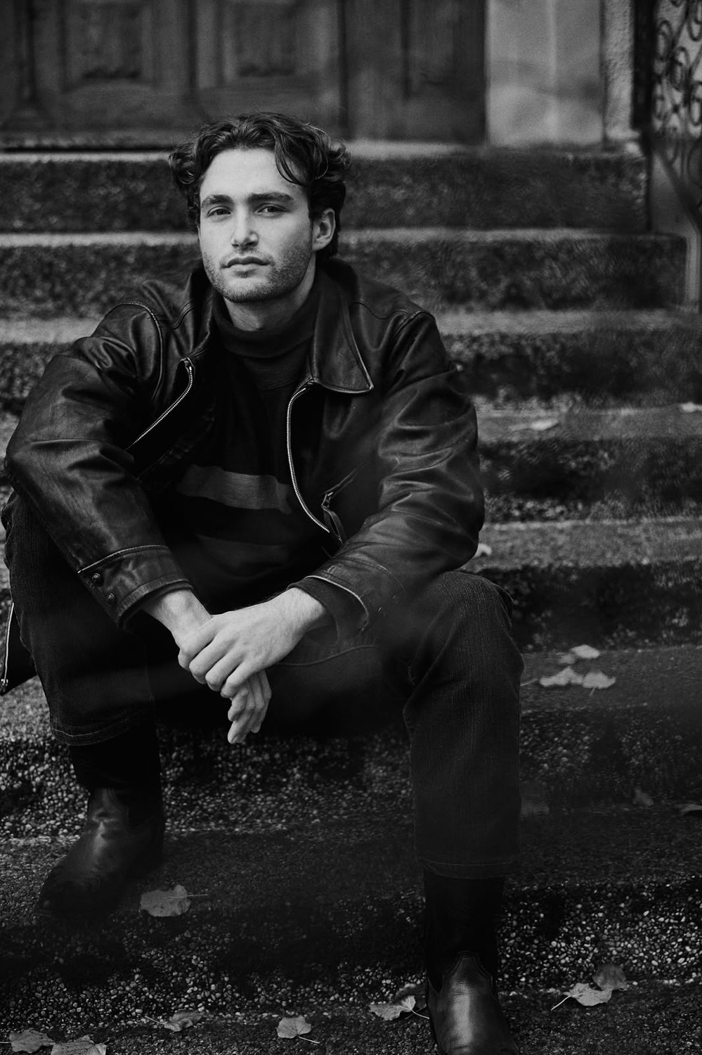 Pascal Sander seated on stone steps in a leather jacket