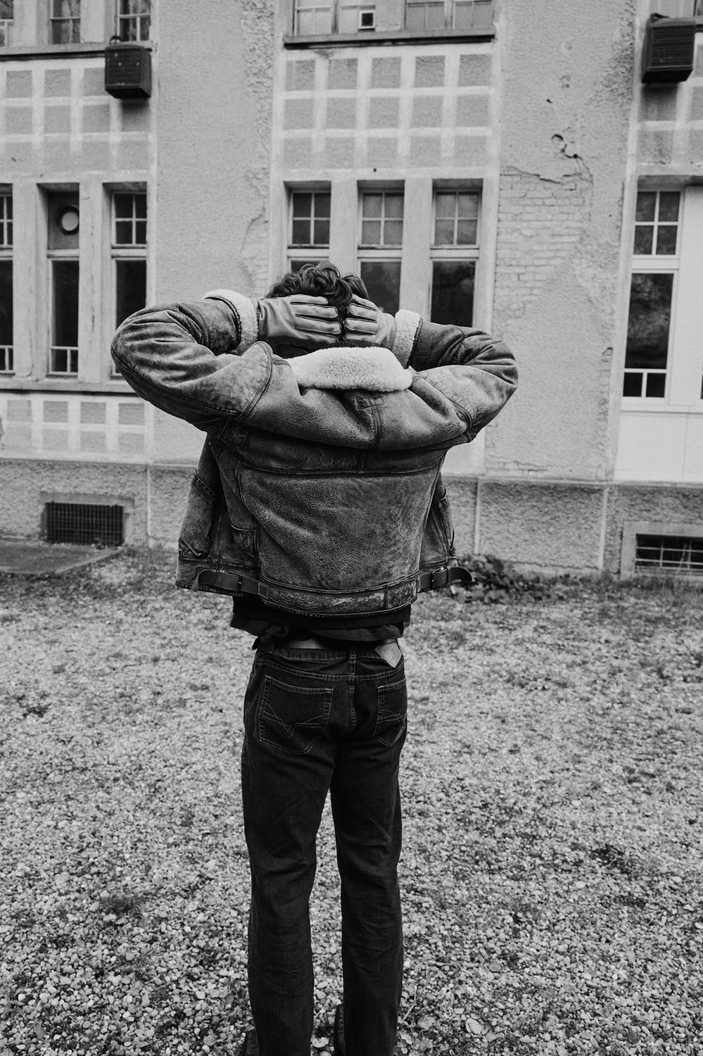 Pascal Sander from behind in a shearling jacket, hands on his head